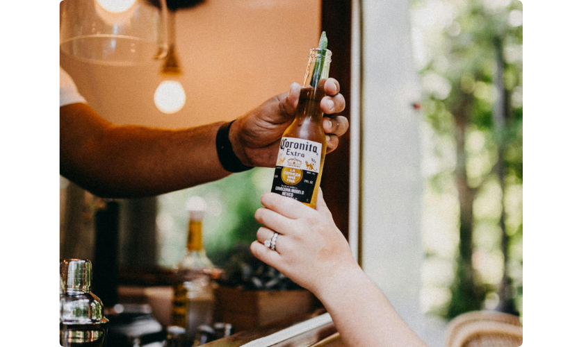 A bottle of corona being passed out at a bar